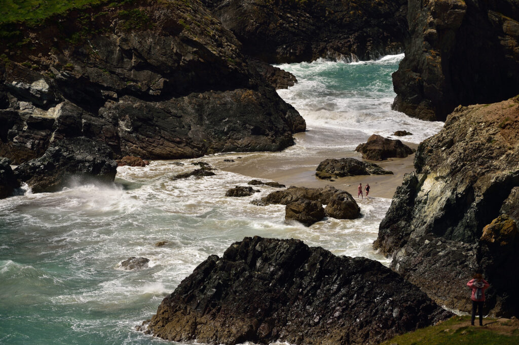 Visitor walking along the coastal path at Kynance Cove, Lizard Peninsula, Cornwall