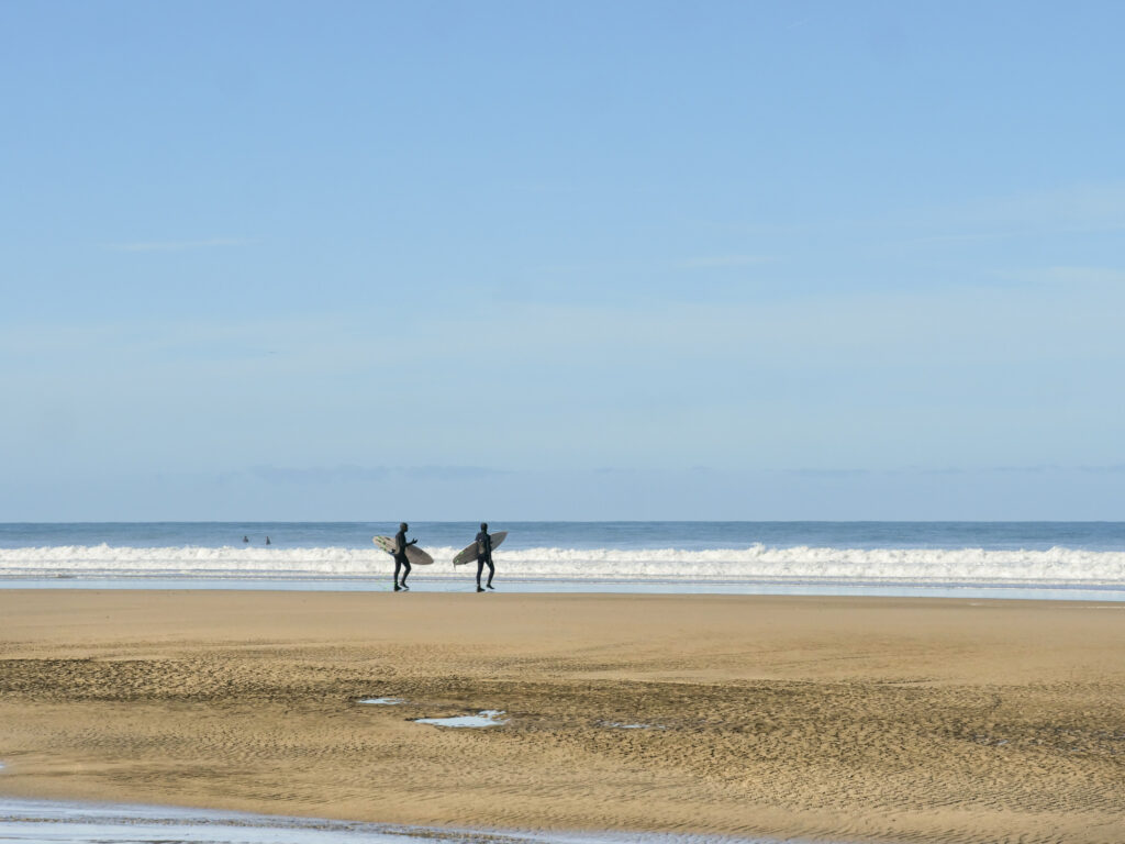 Surfers headed for the waves at Chapel Porth, Cornwall