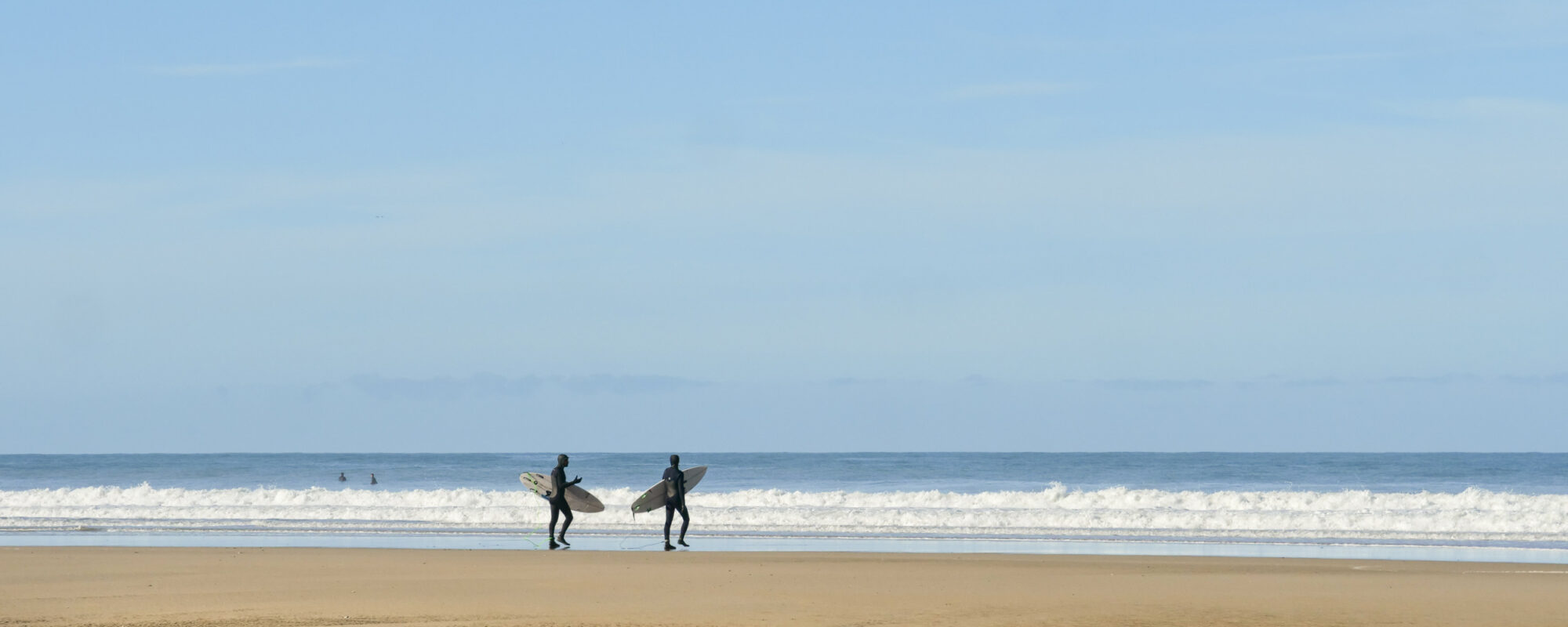Surfers headed for the waves at Chapel Porth, Cornwall