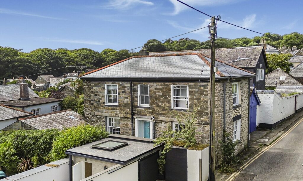 Charming stone built cottage in Cornwall with lush green surroundings and scenic hill views.