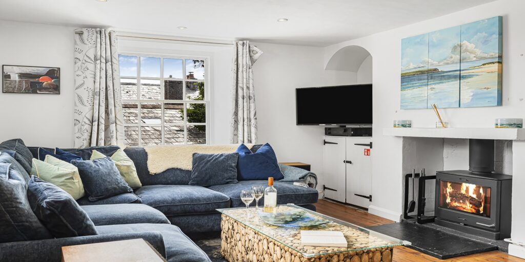 Cozy Cornish cottage living room with fireplace and modern decor, perfect for relaxing holidays.