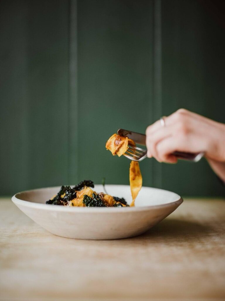 Fresh seafood pasta with black caviar and lemon sauce, served in a white bowl.