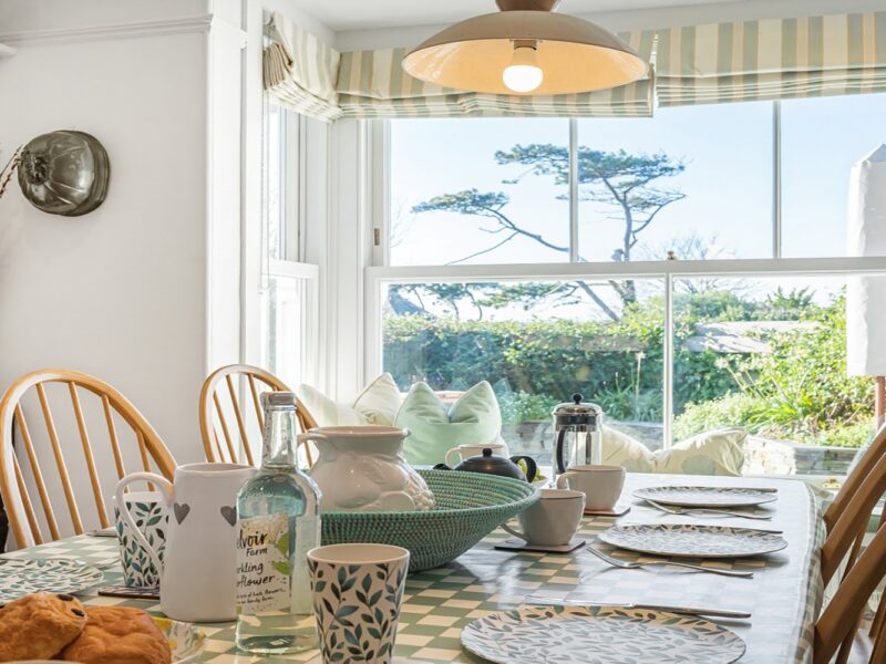 Coastal cottage breakfast room with large bay windows, seaside views, and charming decor for relaxing mornings.