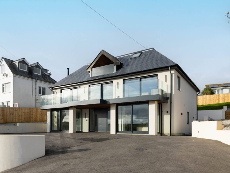 Contemporary coastal home in Cornwall featuring modern architecture, glass balconies, and scenic surroundings.