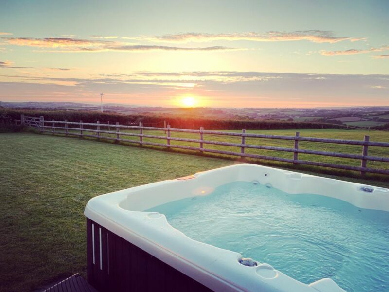 Relaxing hot tub with scenic Cornwall countryside sunset view.