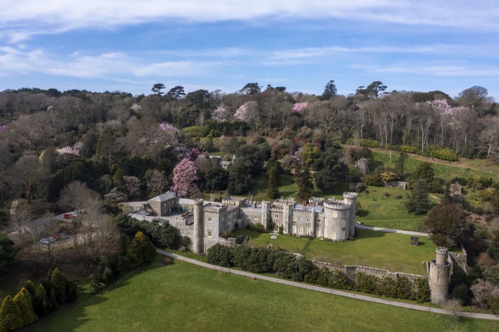 Castle in Cornwall surrounded by lush greenery and blooming trees.