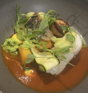 Seafood dish with vegetables, herbs, and sauce at Cornish Secrets restaurant.