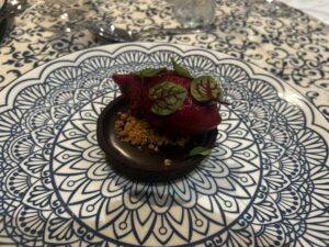 Delicious dessert featuring fresh berries and edible leaves on a decorative plate.