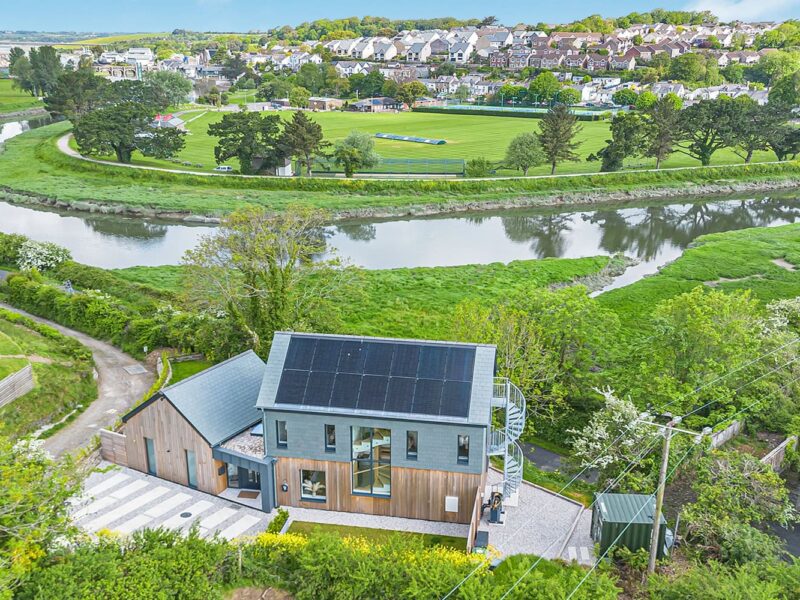 Eco-friendly modern house with solar panels in a lush green landscape.