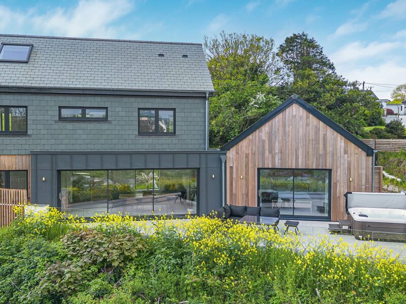 Contemporary house with large glass windows and wooden accents in Cornwall.