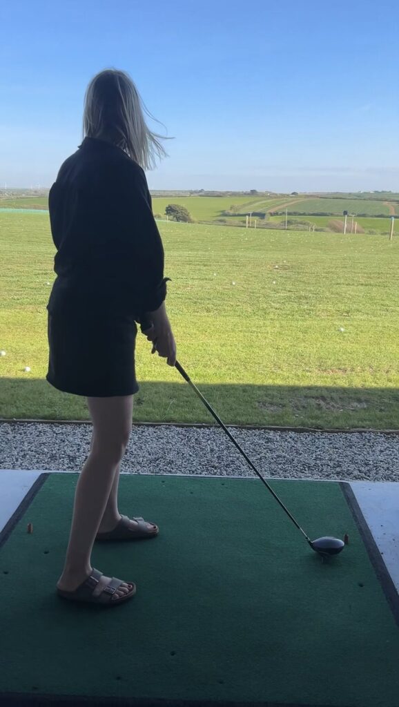 Woman preparing to tee off at Cornish Secrets golf course.