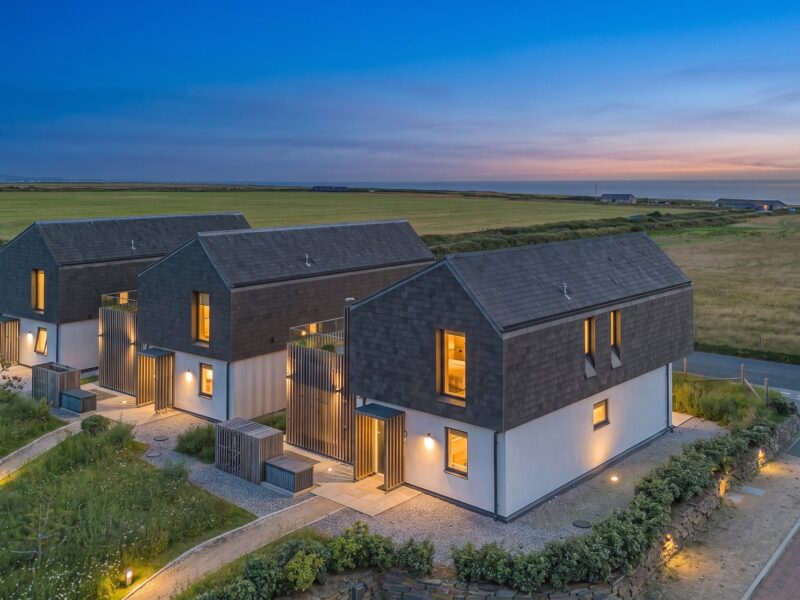 Contemporary seaside houses in Cornwall with scenic coastal views at dusk.