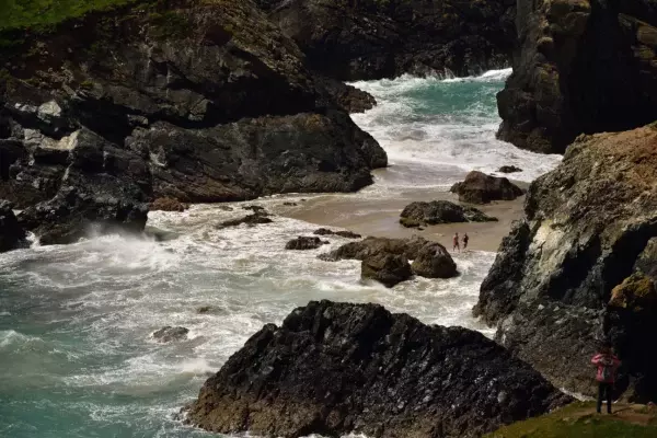Visitor walking along the coastal path at Kynance Cove, Lizard Peninsula, Cornwall
