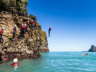 man-jumping-off-rocks-into-sea-768x512