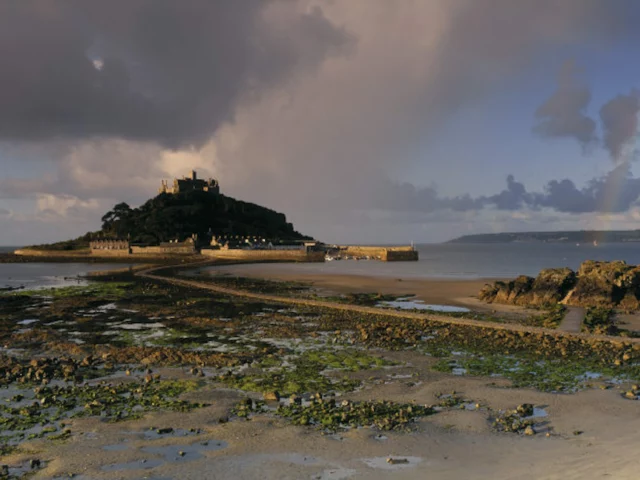 St Michaels Mount seen at low tide with the causeway leading from the sandy beach at Marazion and showing Penzance across the bay in the background. ©National Trust Images David Noton